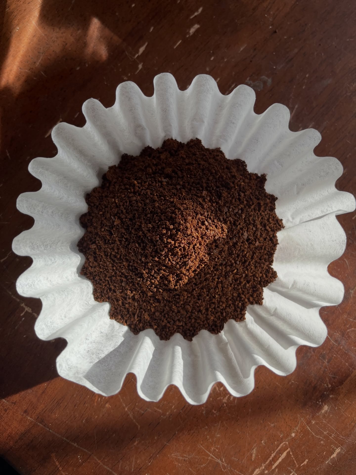 Ground coffee in a white paper filter on a wooden surface